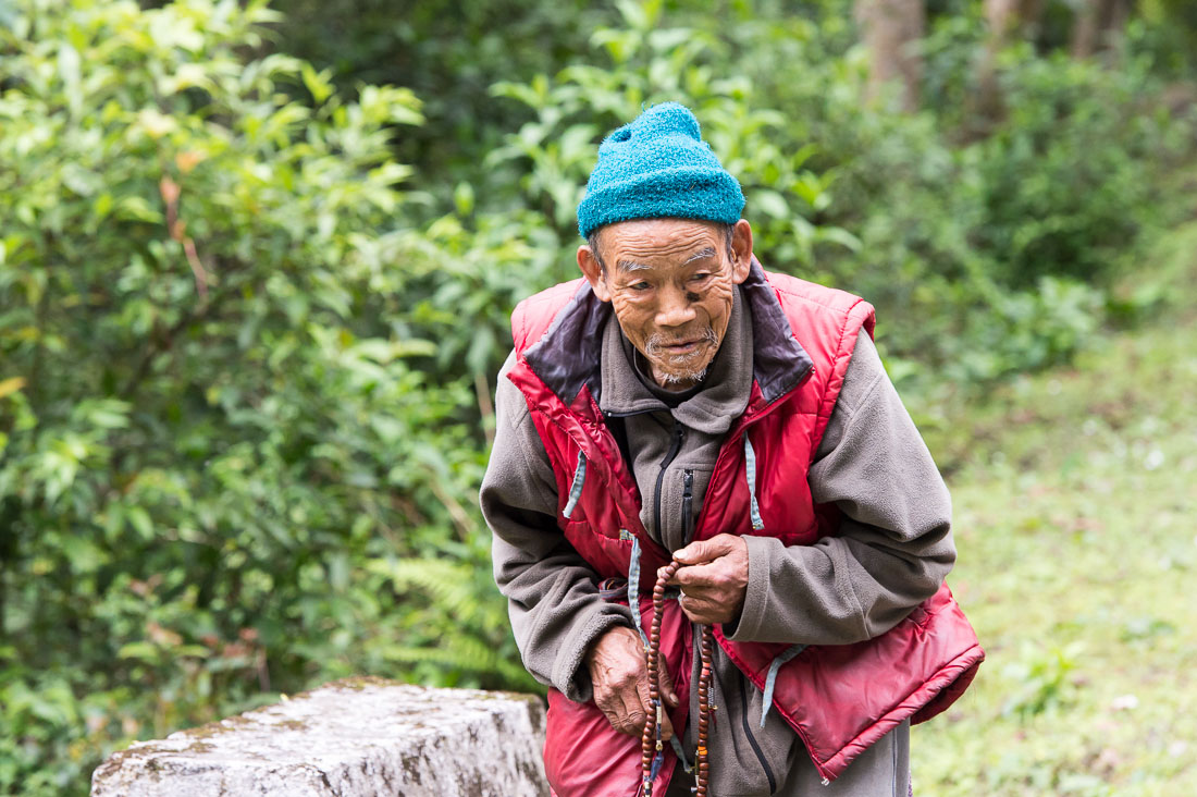 Old man from the countryside praying using the Buddhist malas (prayer beads), Kingdom of Bhutan, Asia