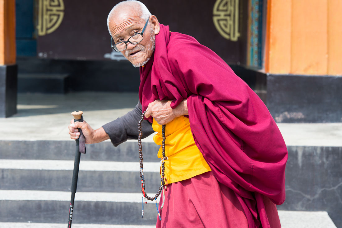 Old man at the Rangjung Buddhist monastery praying using the Buddhist malas (prayer beads) while performing the ritual walking around the temple, Kingdom of Bhutan, Asia
