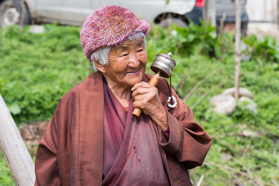 Old woman in the countryside, walking  and spinning her prayer wheel, Kingdom of Bhutan, Asia