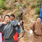 Archer, wearing traditional Bhutanese costume, shooting at 500 feet target using a modern compuond bow Kingdom of Bhutan, Asia