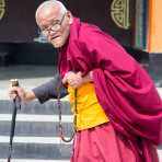 Old man at the Rangjung Buddhist monastery praying using the Buddhist malas (prayer beads) while performing the ritual walking around the temple, Kingdom of Bhutan, Asia