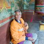 Old man at Punakha Dzong monastery  praying using the Buddhist malas (prayer beads) while performing the ritual spinning of the praying wheel, Kingdom of Bhutan, Asia