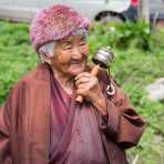 Old woman in the countryside, walking  and spinning her prayer wheel, Kingdom of Bhutan, Asia