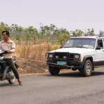 An unusual towing method: a scooter is towing a jeep using a small rope! Kingdom of Cambodia, Indochina, South East Asia.