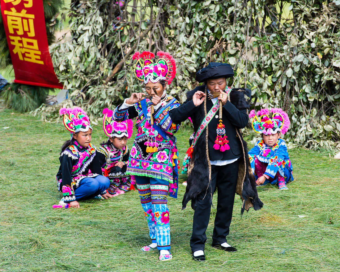 A man and a woman from the Yi ethnic minority people, playing a primitive musical instrument, in traditional colorful costumes at the annual festival in Zhi Ju village, Yong Ren County, Yunnan Province, China, Asia. Nikon D4, 70-200mm, f/2.8, VR II