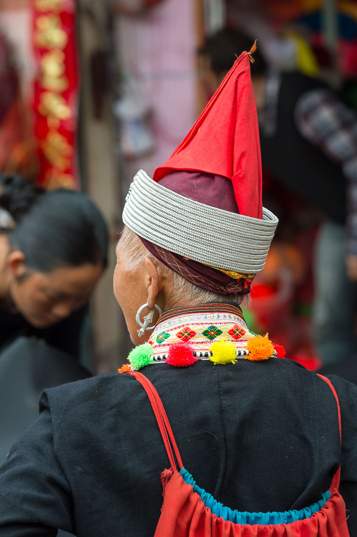 The unconventional hat worn by  the women from the Yao ethnic minority people. Jin Ping market, Yunnan Province, China, Asia. Nikon D4, 70-200mm, f/2.8, VR II