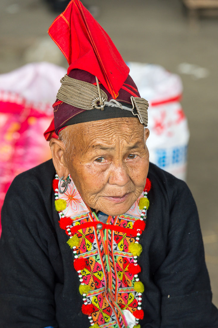 An old woman from the Yao ethnic minority people wearing the traditional costume. Jin Ping market, Yunnan Province, China, Asia. Nikon D4, 70-200mm, f/2.8, VR II
