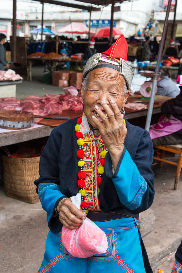 A joyful woman from the Yao ethnic minority people, in traditional costume, smiling at the photographer. Jin Ping market, Yunnan Province, China, Asia. Nikon D4, 24-120mm, f/4.0, VR