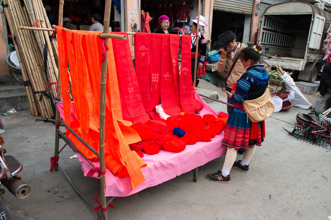 Woman from the Miao ethnic minority people wearing the traditional costume at Jin Ping market buying colorful cotton yarn. Jin Ping County, Yunnan Province, China, Asia. Nikon D4, 24-120mm, f/4.0, VR