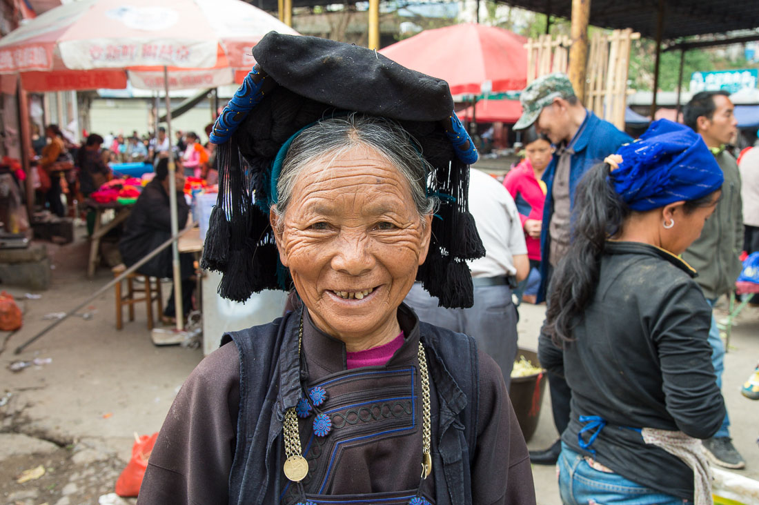 A joyful woman from the Ha Ni ethnic minority people, wearing the traditional costume,  at Jin Shui He market, Jin Ping County, Yunnan Province, China, Asia. Nikon D4, 24-120mm, f/4.0, VR