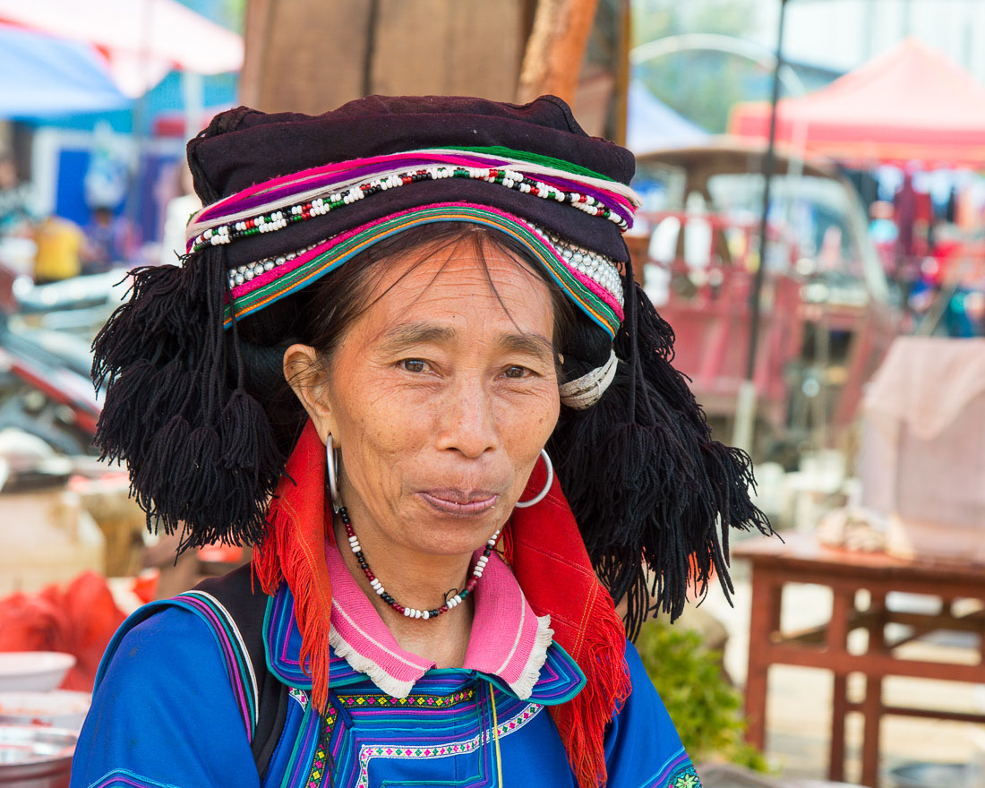 A joyfull woman from the Yi ethnic minority people, wearing the traditional costume,  at Jin Shui He market, Jin Ping County, Yunnan Province, China, Asia. Nikon D4, 24-120mm, f/4.0, VR