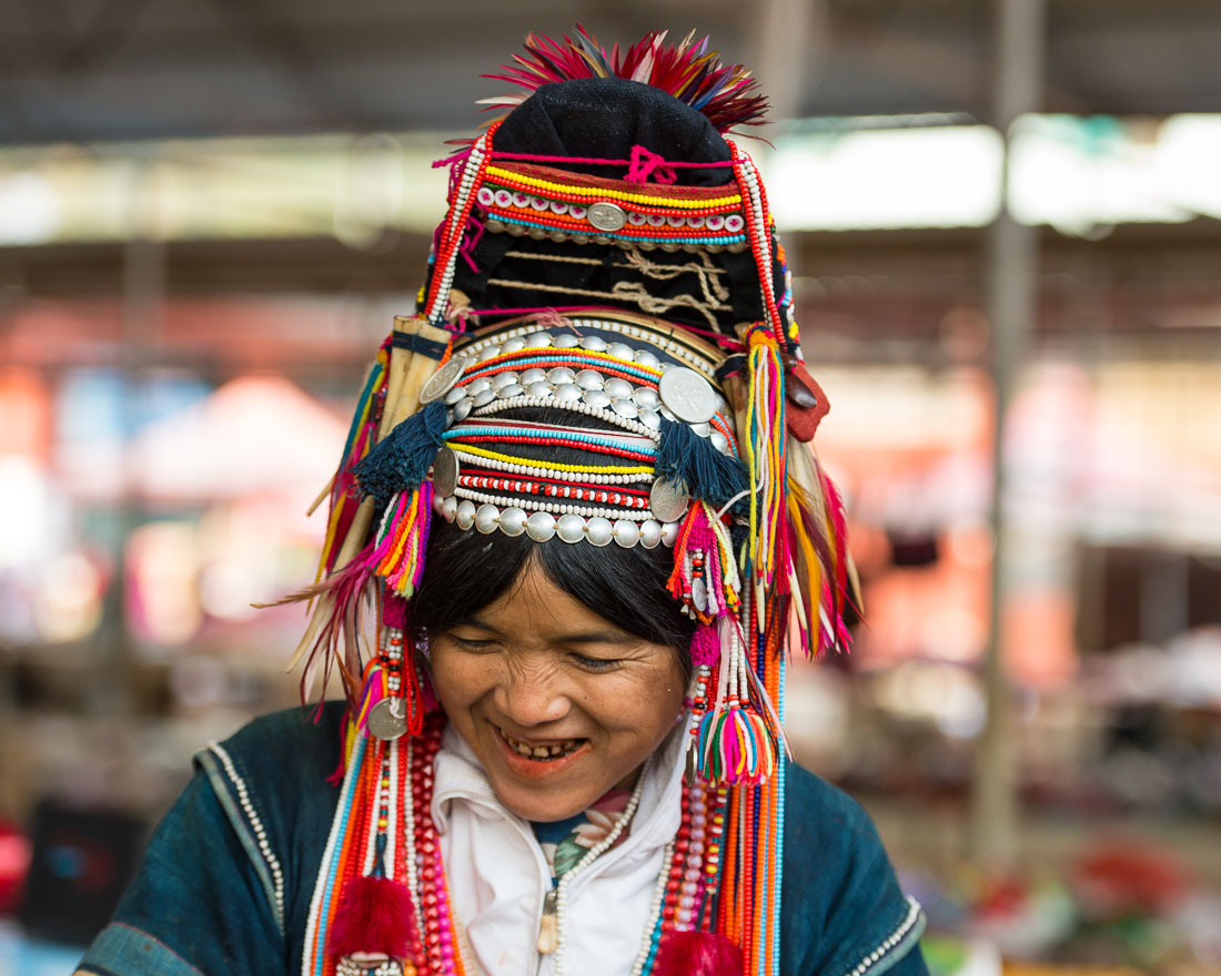 A joyfull woman from the Ha Ni ethnic minority people in colorful costume, at Mang Xin market, Meng Lian County, Yunnan Province, China, Asia. Nikon D4, 70-200mm, f/2.8, VR II