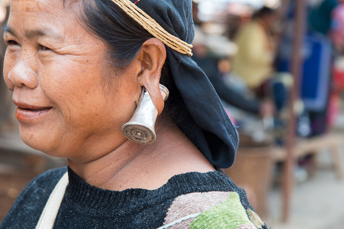 A woman from the Bulang ethnic minority people wearing the unique traditional earring. Mang Xin market, Meng Lian County, Yunnan Province, China, Asia. Nikon D4, 70-200mm, f/2.8, VR II