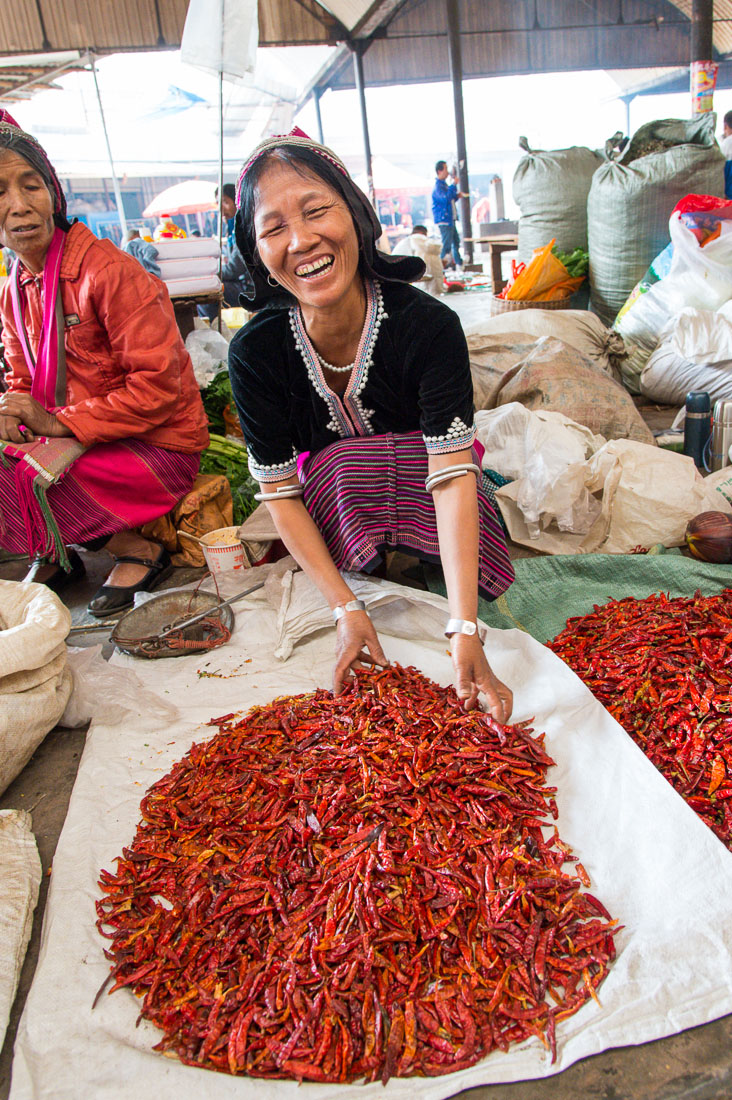 A smiling woman from the Bulang ethnic minority people, selling red chili at the Fu Yen market in Meng Lian County. Yunnan Province, China, Asia. Nikon D4, 24-120mm, f/4.0, VR