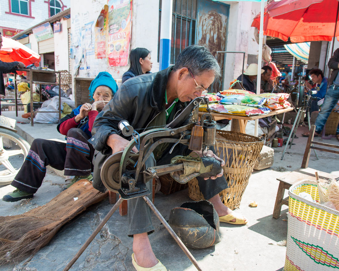 Cobbler at work; Jia Yin market, Yunnan Province, China, Asia. Nikon D4, 24-120mm, f/4.0, VR