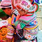 A mother from the Yi ethnic minority people carrying her baby, wearing traditional costume at the Sha La Tuo market, Yang Yang county, Yunnan Procince, China, Asia. Nikon D4, 24-120mm, f/ 4.0, VR.