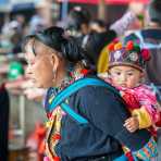 A grandma from the Yao ethnic minority people carrying her grandson, wearing traditional costume at the Jin Ping market, Yang Yang county, Yunnan Procince, China, Asia. Nikon D4, 70-200mm, f/2.8, VR II.