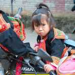 A little girl from the Yao ethnic minority people, in traditional costume, apparently scared by my camera, at the Jin Shui He town market, Yunnan Procince, China, Asia. Nikon D4, 24-120mm, f/ 4.0, VR.