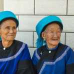 Two joyful old women from the Yi ethnic minority people in their traditional costumes at the market in Jia Yin village. Yunnan Province, China, Asia. Nikon D4, 24-120mm, f/4.0, VR