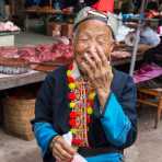 A joyful woman from the Yao ethnic minority people, in traditional costume, smiling at the photographer. Jin Ping market, Yunnan Province, China, Asia. Nikon D4, 24-120mm, f/4.0, VR