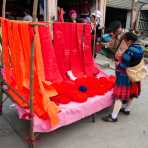 Woman from the Miao ethnic minority people wearing the traditional costume at Jin Ping market buying colorful cotton yarn. Jin Ping County, Yunnan Province, China, Asia. Nikon D4, 24-120mm, f/4.0, VR