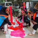 Women from the Yao ethnic minority people wearing the traditional costume at Jin Shui He market buying colorful cotton yarn. Jin Ping County, Yunnan Province, China, Asia. Nikon D4, 24-120mm, f/4.0, VR