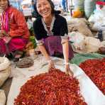 A smiling woman from the Bulang ethnic minority people, selling red chili at the Fu Yen market in Meng Lian County. Yunnan Province, China, Asia. Nikon D4, 24-120mm, f/4.0, VR