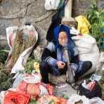 An old woman from the Miao ethnic minority people, smoking a bong handmade from plastic bottles. She sells medicinal herbs at the Jin Ping market. Yunnan Province, China, Asia. Nikon D4, 24-120mm, f/4.0, VR