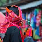 A woman from the Akha people ethnic minority wearing her traditional costume and an elaborate hat, at a village's market in Phongsali province. Lao PDR, Indochina, South East Asia
