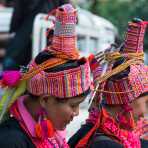 Two women from the Akha people ethnic minority wearing her traditional costume and an elaborate hat, at a village's market in Phongsali province. Lao PDR, Indochina, South East Asia