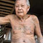 Old man from the Tailue people ethnic minority, showing his torso covered with tattoos. Xieng Kokkao village, Luang Namtha province, Lao PDR, Indochina, South East Asia.