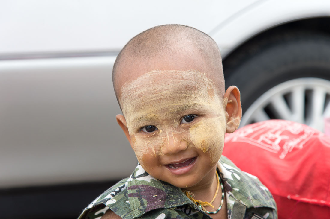 Little boy smiling, his face covered by patches of Tha Nat Khar an extract from tree rooths used by the Burmese people to protect the skin from sun, Yangon, Myanmar, Indochina, South East Asia.