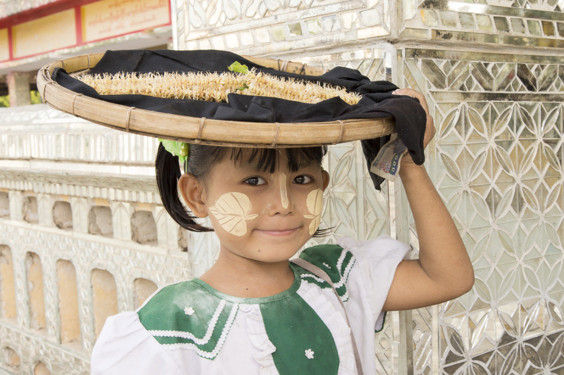 Little girl, still in school uniform, selling flowers at the Kutodaw Pagoda, Mandaley, Myanmar, Indochina, South East Asia.