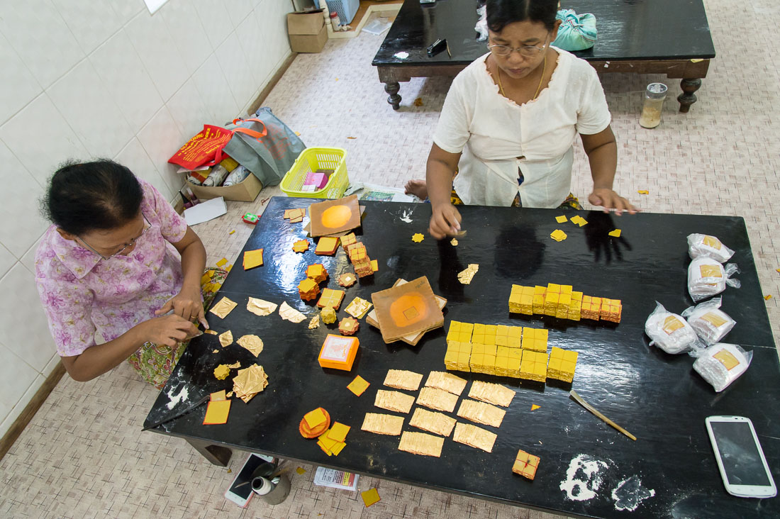 Preparing gold leaves used to cover Buddha statues and pagodas. Mandalay, Myanmar, Indochina, South East Asia.