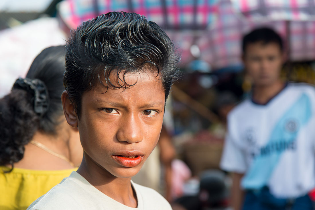 Handsome young boy, with western style hairdo, with red lips because of his addiction of chewing paan (areca nuts and betel leaves).  Sittwe, Rakhine State, Myanmar, Indochina, South East Asia