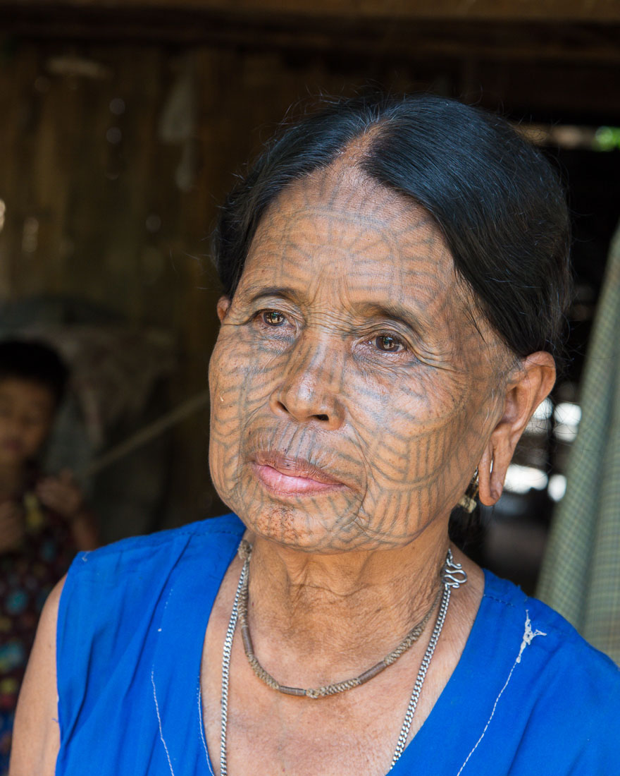 Old woman with the face full covered from spider web tattos, a mysterious and old tradition which was practiced until 60 years ago. There are 7 villages on the Lamro river with about 20 old women left with spider web tattoos on their face, all aged more than 65 years. Chin Village, Rakhine State, Myanmar, Indochina, South East Asia.