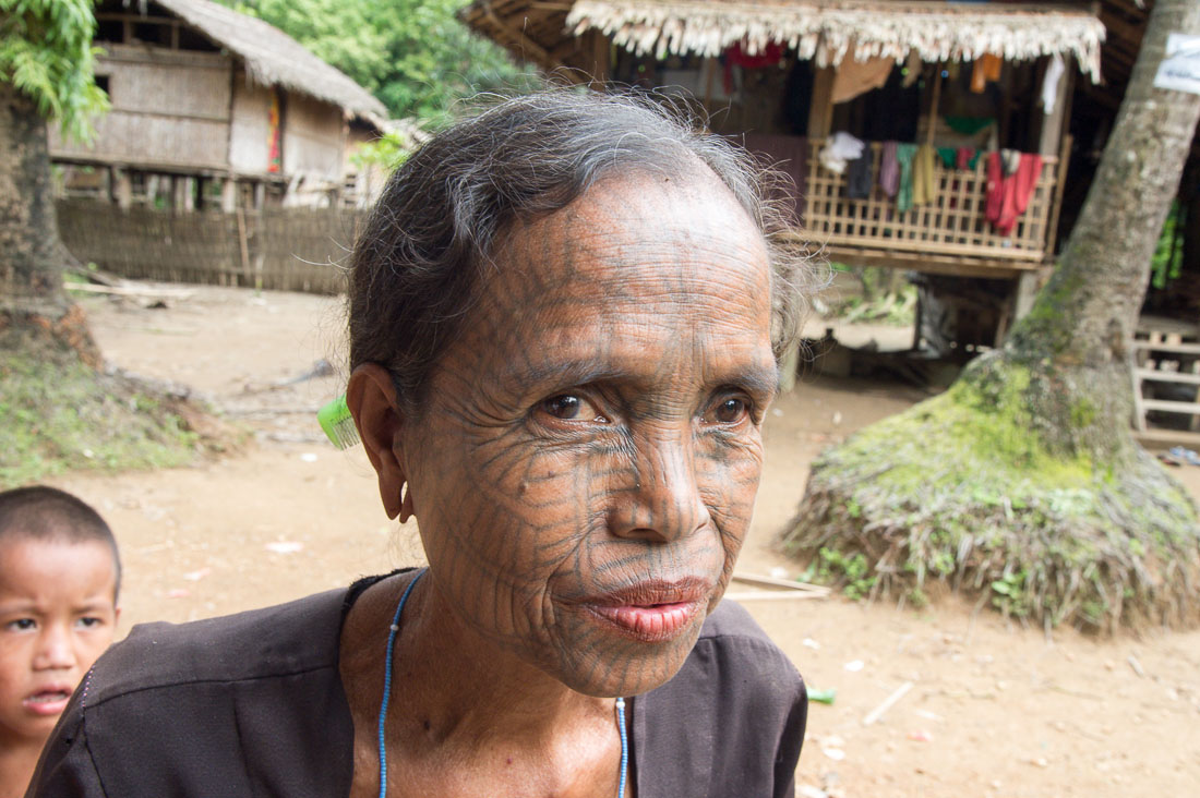 Old woman with the face full covered from spider web tattos, a mysterious and old tradition which was practiced until 60 years ago. There are 7 villages on the Lamro river with about 20 old women left with spider web tattoos on their face, all aged more than 65 years. Chin Village, Rakhine State, Myanmar, Indochina, South East Asia.