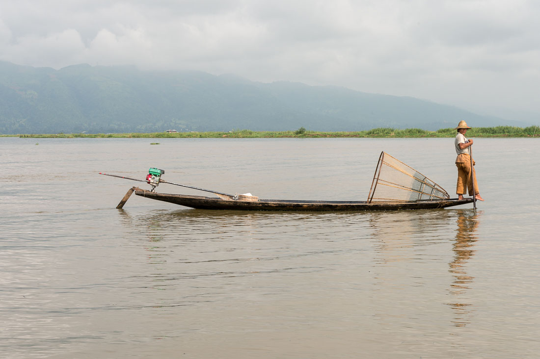 A fisherman with his creel, traditionally leg rowing, Inle Lake, Shan State, Myanmar, Indochina, South East Asia.