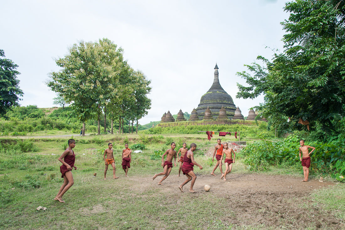 Young novice Buddhist monks playing soocer (football) just in front of Ratanabon Pagoda, in late afternoon, Mrauk U Village, Rakhine State, Myanmar, Indochina, South East Asia.
