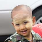 Little boy smiling, his face covered by patches of Tha Nat Khar an extract from tree rooths used by the Burmese people to protect the skin from sun, Yangon, Myanmar, Indochina, South East Asia.