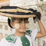 Little girl, still in school uniform, selling flowers at the Kutodaw Pagoda, Mandaley, Myanmar, Indochina, South East Asia.