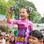 Smiling and happy little girl on her father shoulders taking pictures of the parade. Manhua Village, Myanmar, Indochina, South East Asia