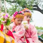 Two little girls wearing costumes, riding an animated tiger made out of paper mache, Manhua Village, Myanmar, Indochina, South East Asia