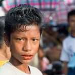 Handsome young boy, with western style hairdo, with red lips because of his addiction of chewing paan (areca nuts and betel leaves).  Sittwe, Rakhine State, Myanmar, Indochina, South East Asia