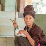 Old beggar smoking a cigar on the stairs of the Buddhist religious site of Mount Popa, Myanmar, Indochina, South East Asia.