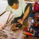 A disabled person and talented artist, born with one limb only, his left leg and foot,  detailing a bamboo lacquer bowl using a small brush with his foot. Shwe Indein pagoda, Indein Village, Inle lake, Shan State, Mynamar, Indochina, South East Asia.