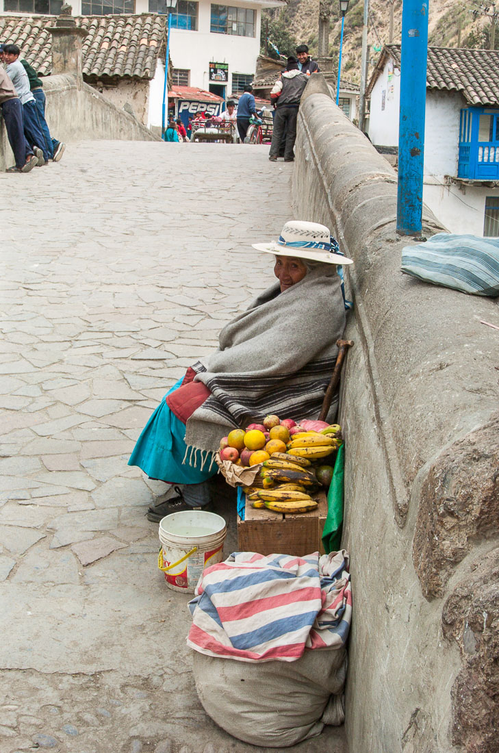 Old woman selling fruits on the bridge of Pilcopata, Peru, South America