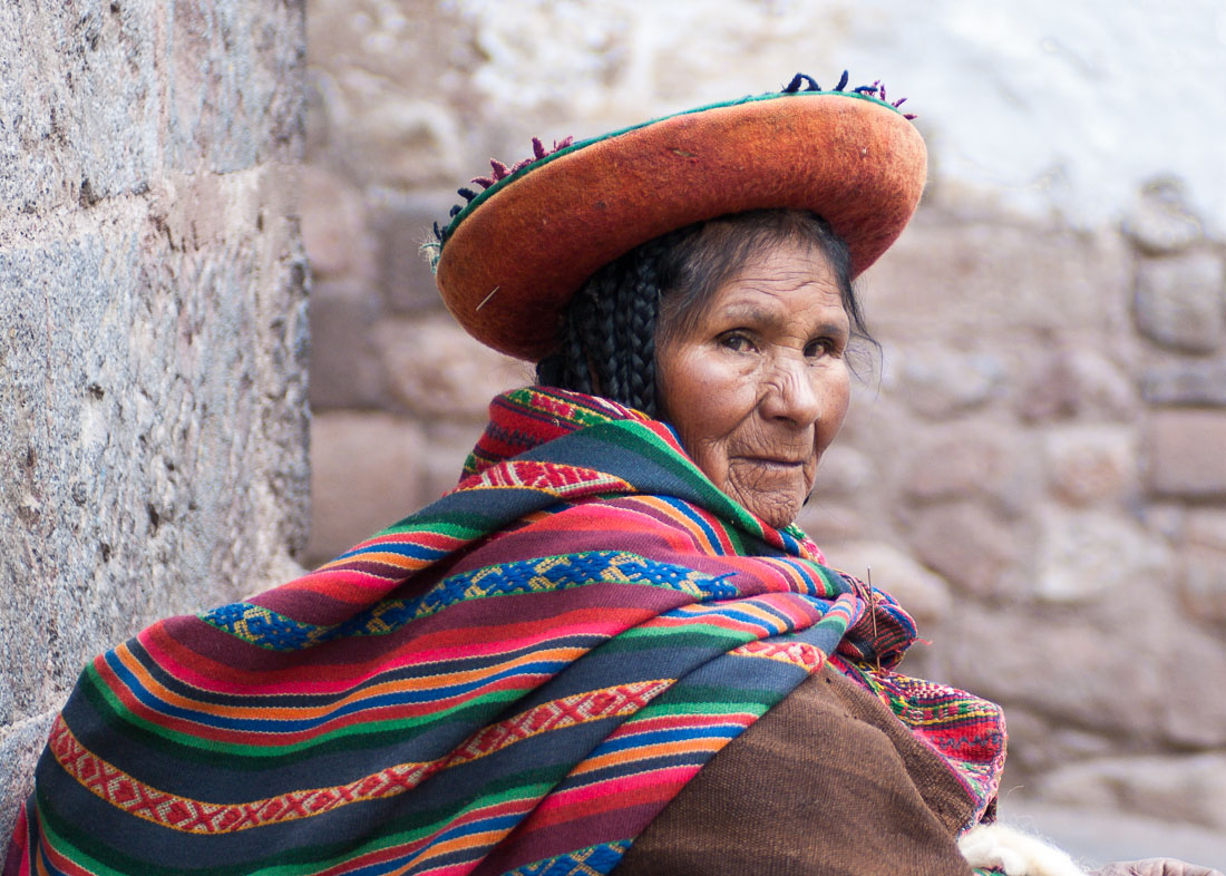 Woman wearing traditional costume and hat spinning wool in the street of Cuzco, Peru, South America