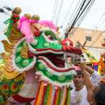 Worshippers throwing alms in the mouth of a Chinese dragon on the street of Phuket during the annual Chinese vegetarian festival. Kingdom of Thailand, Indochina, South East Asia