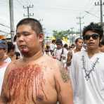 Psychic medium follower of the Bang New Shrine, his chest covered by blood from self inflicted injuries on his face, taking part in a street procession during the annual Chinese vegetarian festival. Phuket, Kingdom of Thailand, Indochina, South East Asia